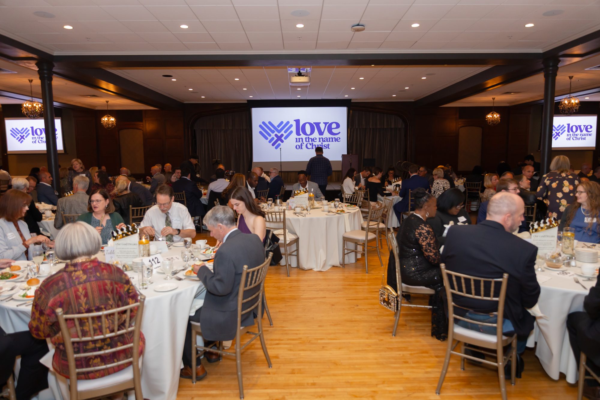 Ballroom full of people with Love INC logo on the screen